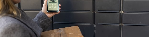 Young woman using smart phone while testing smart locker implementation at a school using device to unlock