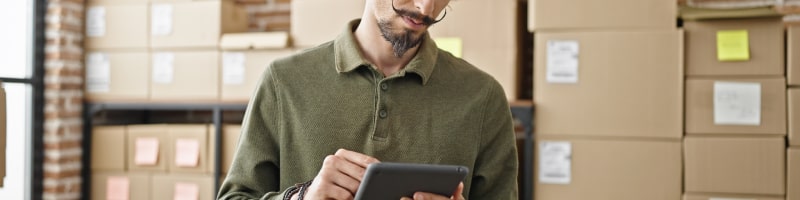 Young man using ipad to track shipment delivery through mobile responsive desktop shipping software