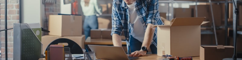 Man in mail center scanning package into desktop shipping software with rate shopping